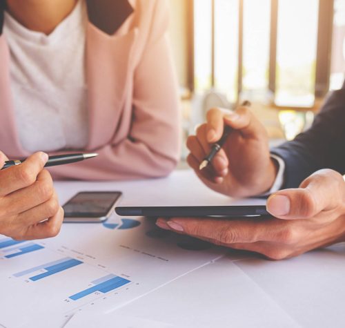 Business concept. Business people discussing the charts and graphs showing the results of their successful teamwork. Selective focus.