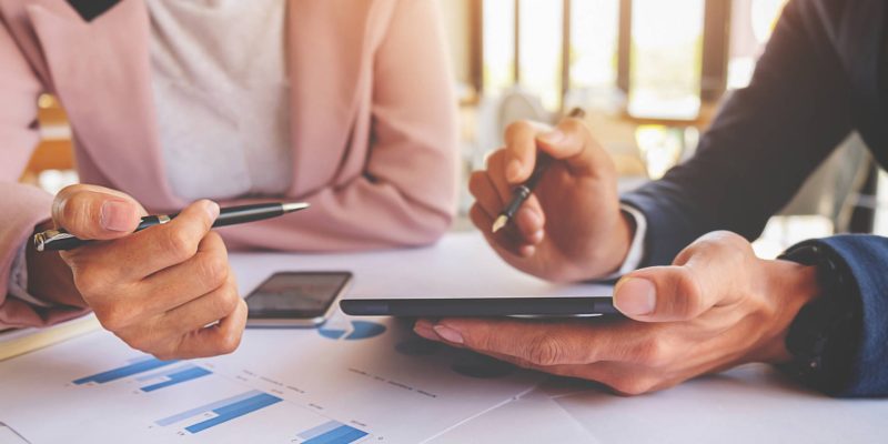 Business concept. Business people discussing the charts and graphs showing the results of their successful teamwork. Selective focus.