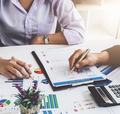 Business financial concept. busines sman and partner pointing graph paper are meeting to plan sales to meet targets set in next year.