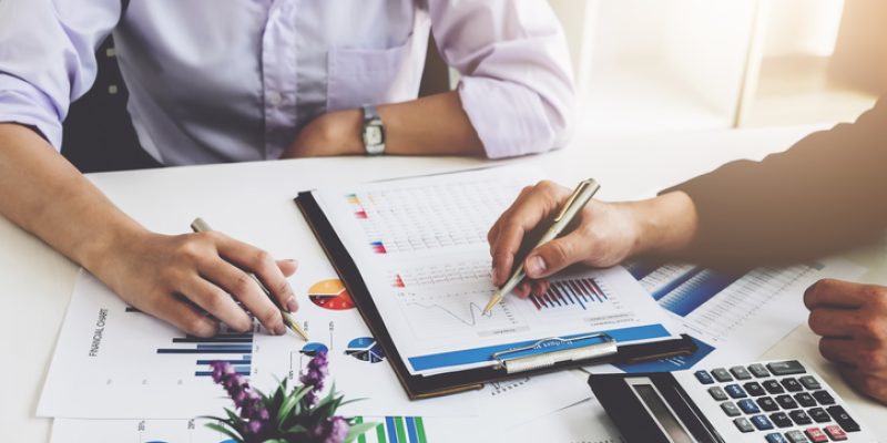 Business financial concept. busines sman and partner pointing graph paper are meeting to plan sales to meet targets set in next year.